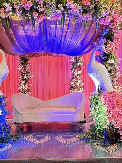 Peacock themed stage with pink florals and blue lighting